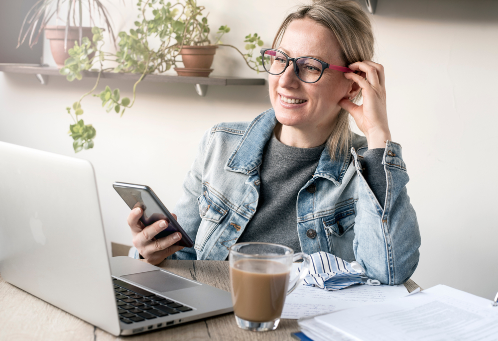 a blond woman sitting at her desk happily working from home 