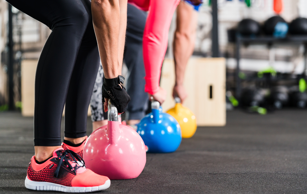 a line of three people using dumbbells to workout